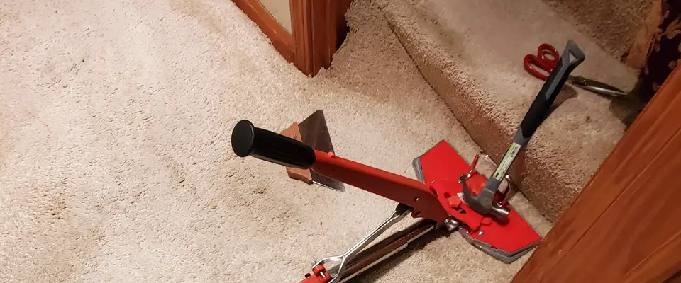 carpet being stretch and repaired at the bottom of a stairway